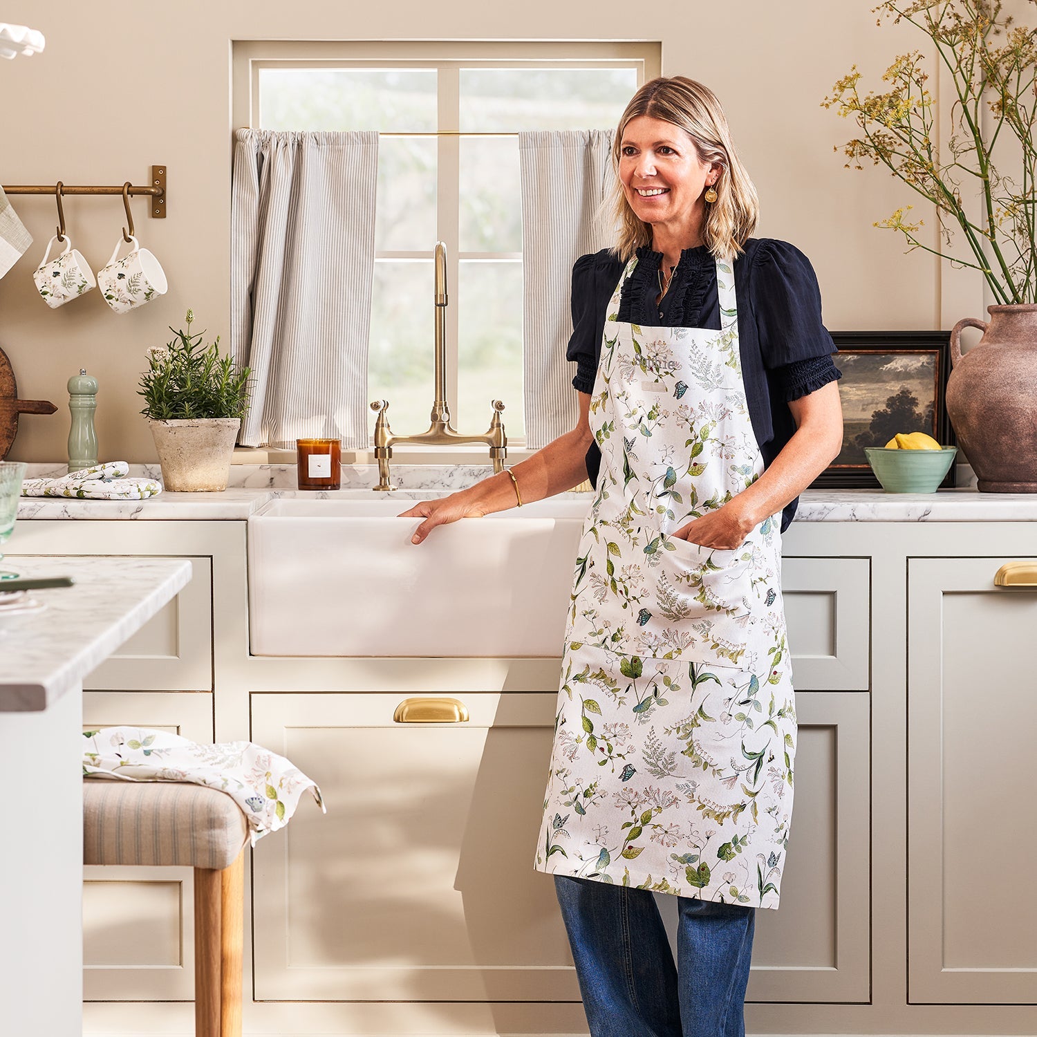 White floral print adult apron by Sophie Allport modelled in kitchen