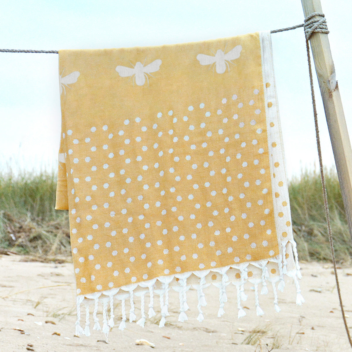 Sophie Allport's yellow hammam towel covered white bees, perfect for the park or beach.